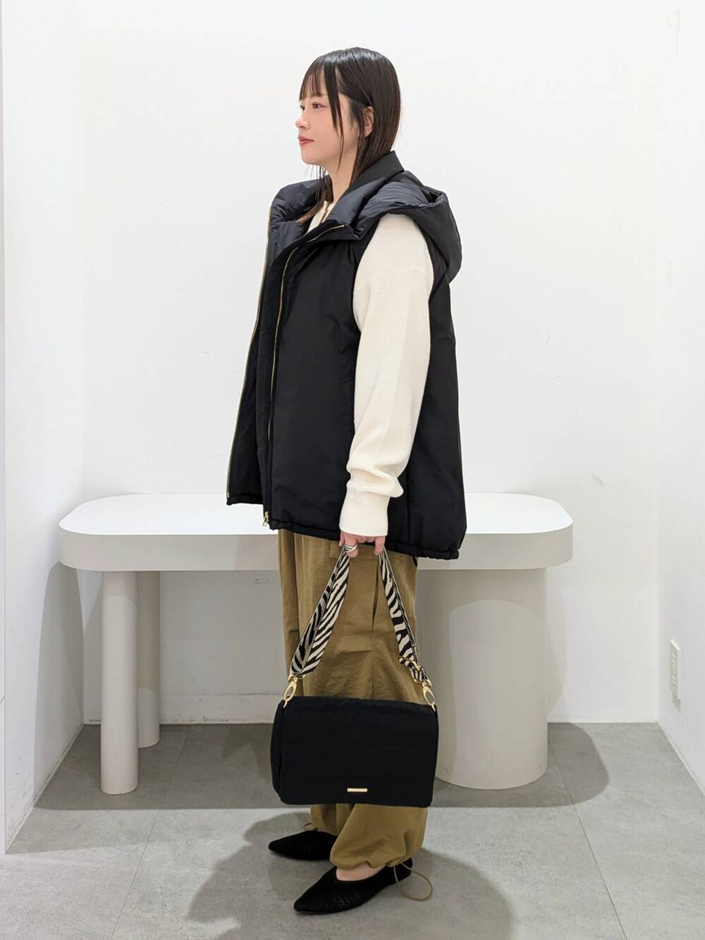 ホワイト系のニット/セーター、イエロー系のカーゴパンツ、ブラック系のその他アウターを着用したレディースの秋コーディネートの3枚目の写真