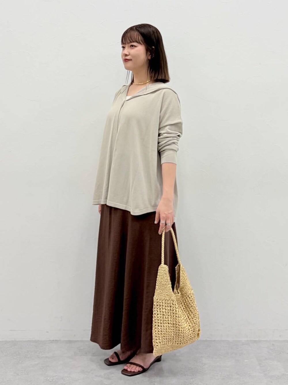 ゴールド系のトートバッグ、ブラウン系のサンダル、ブラウン系のスカートを着用したレディースの夏コーディネートの3枚目の写真