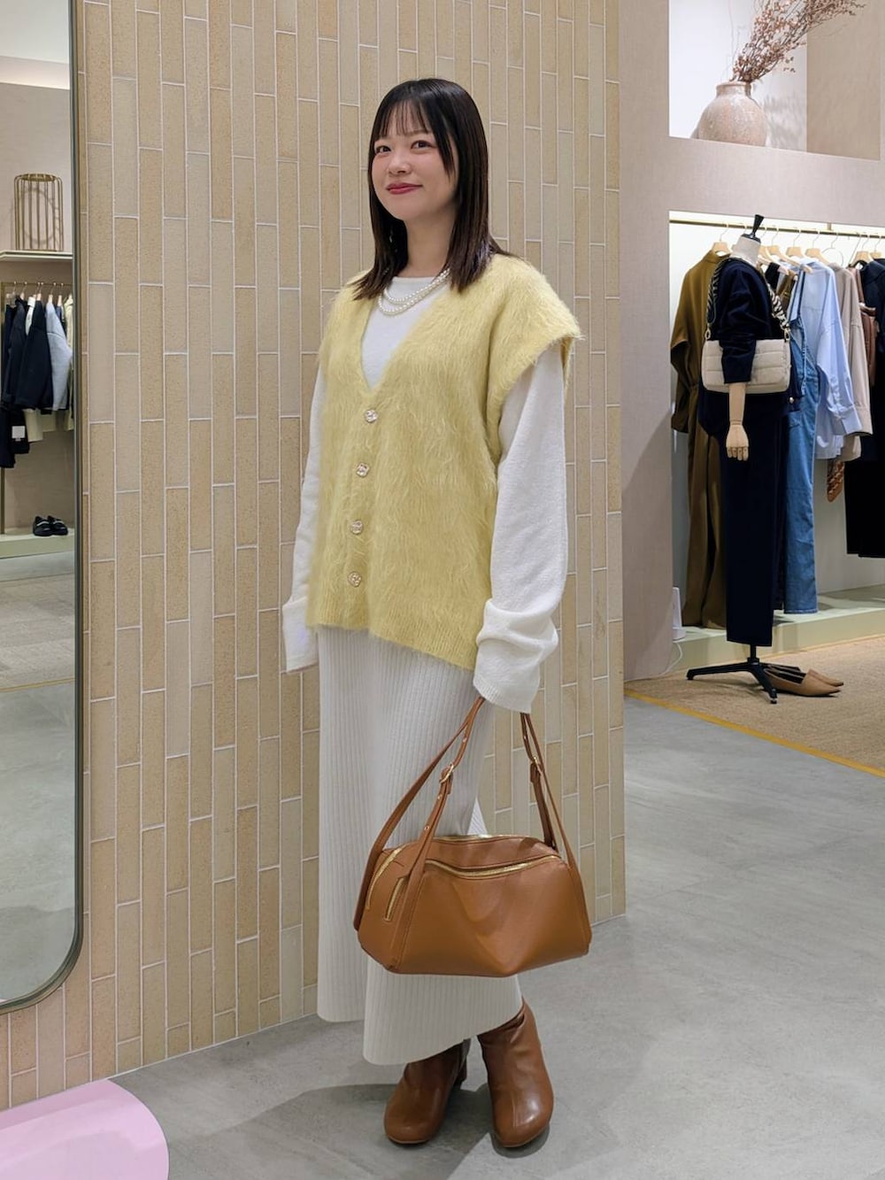 ベージュ系のスカート、ブラウン系のブーツ、ブラウン系のショルダーバッグを着用したレディースの秋コーディネートの3枚目の写真