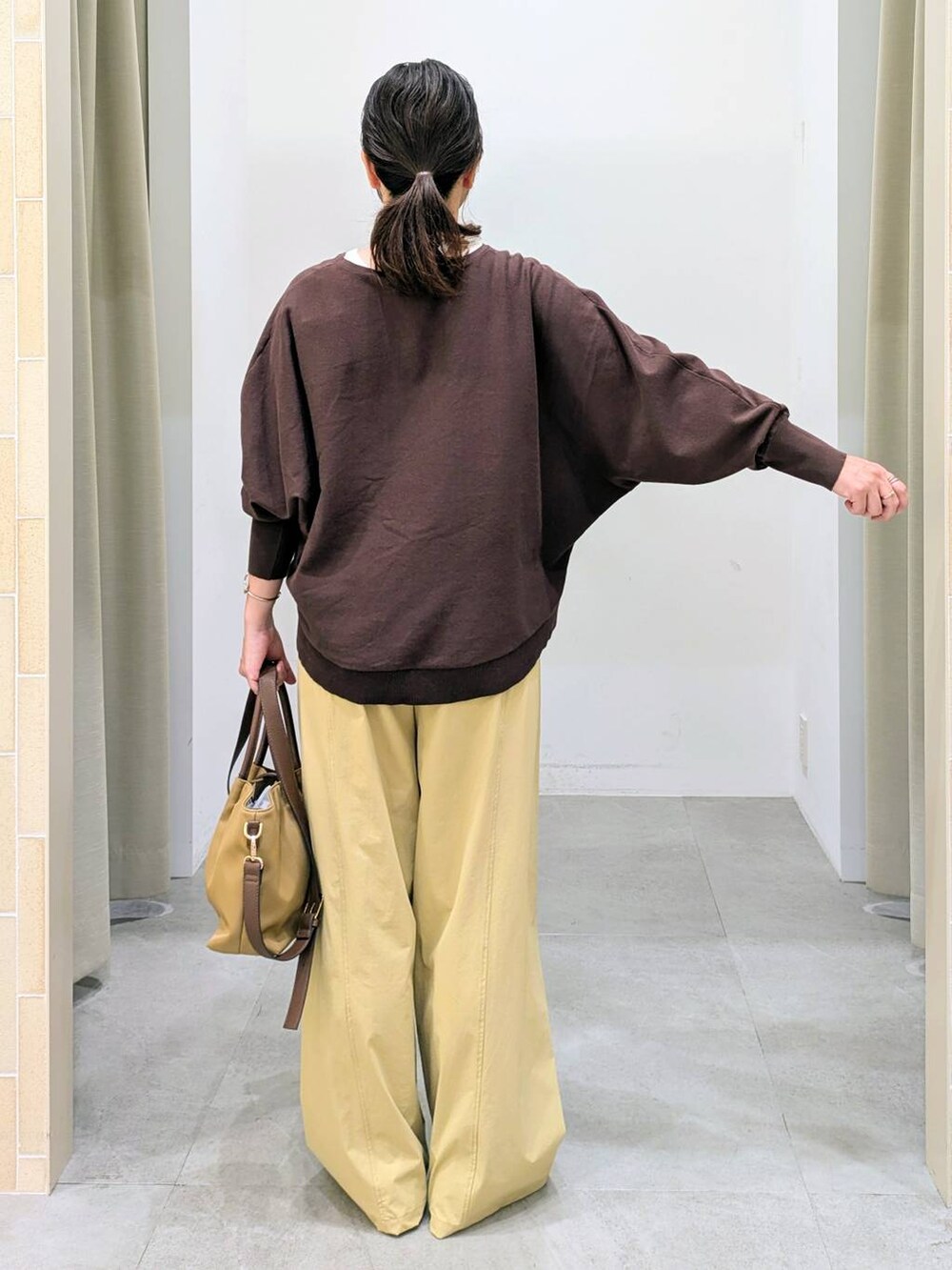 ブラウン系のパンプス、ベージュ系のハンドバッグ、ブラウン系のニット/セーターを着用したレディースの秋コーディネートの4枚目の写真