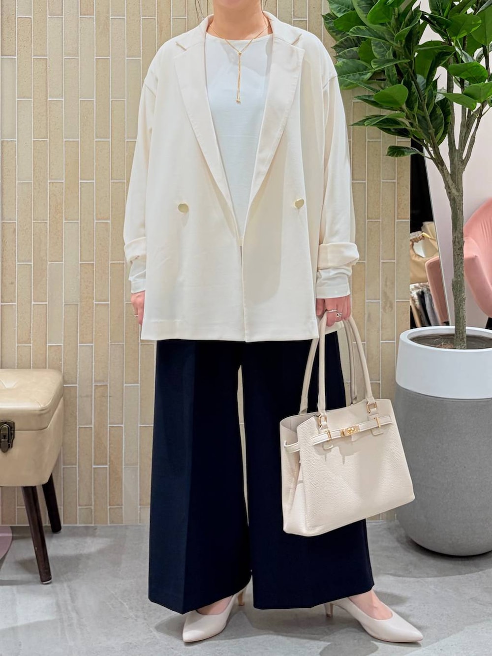 ホワイト系のパンプス、ブルー系のスラックス、ホワイト系のハンドバッグを着用したレディースの春コーディネートの6枚目の写真