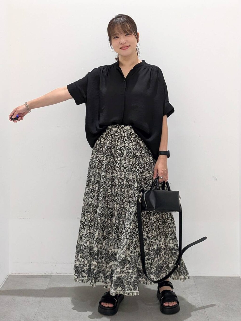 ブラック系のスカート、ブラック系のサンダル、ブラック系のTシャツ/カットソーを着用したレディースの夏コーディネートの2枚目の写真