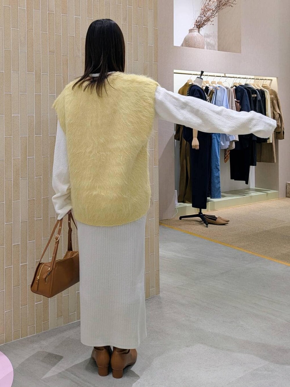 ベージュ系のスカート、ブラウン系のブーツ、ブラウン系のショルダーバッグを着用したレディースの秋コーディネートの4枚目の写真