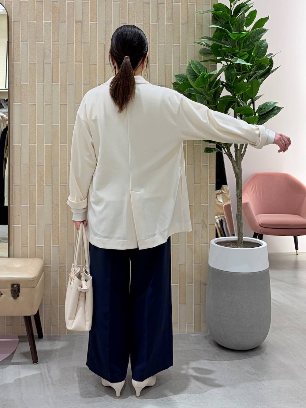 ホワイト系のパンプス、ブルー系のスラックス、ホワイト系のハンドバッグを着用したレディースの春コーディネートの4枚目の写真