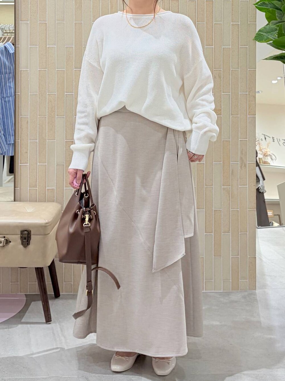 ホワイト系のニット/セーター、ブラウン系のハンドバッグ、ベージュ系のスカートを着用したレディースの春コーディネートの6枚目の写真