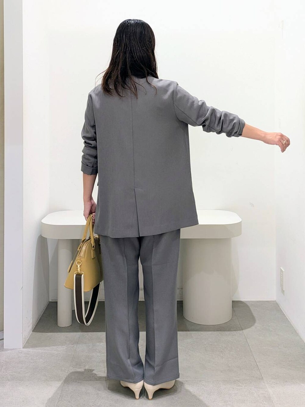 ホワイト系のパンプス、ベージュ系のハンドバッグ、グレー系のその他パンツを着用したレディースの秋コーディネートの4枚目の写真