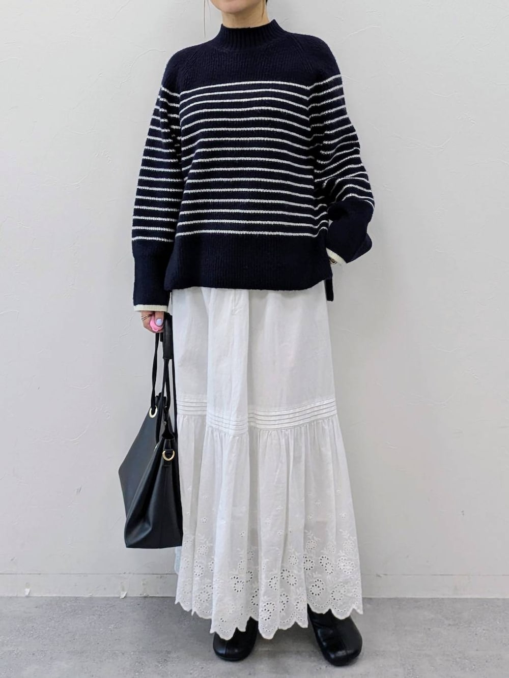 ブラック系のブーツ、ブルー系のニット/セーター、ホワイト系のスカートを着用したレディースの冬コーディネートの6枚目の写真