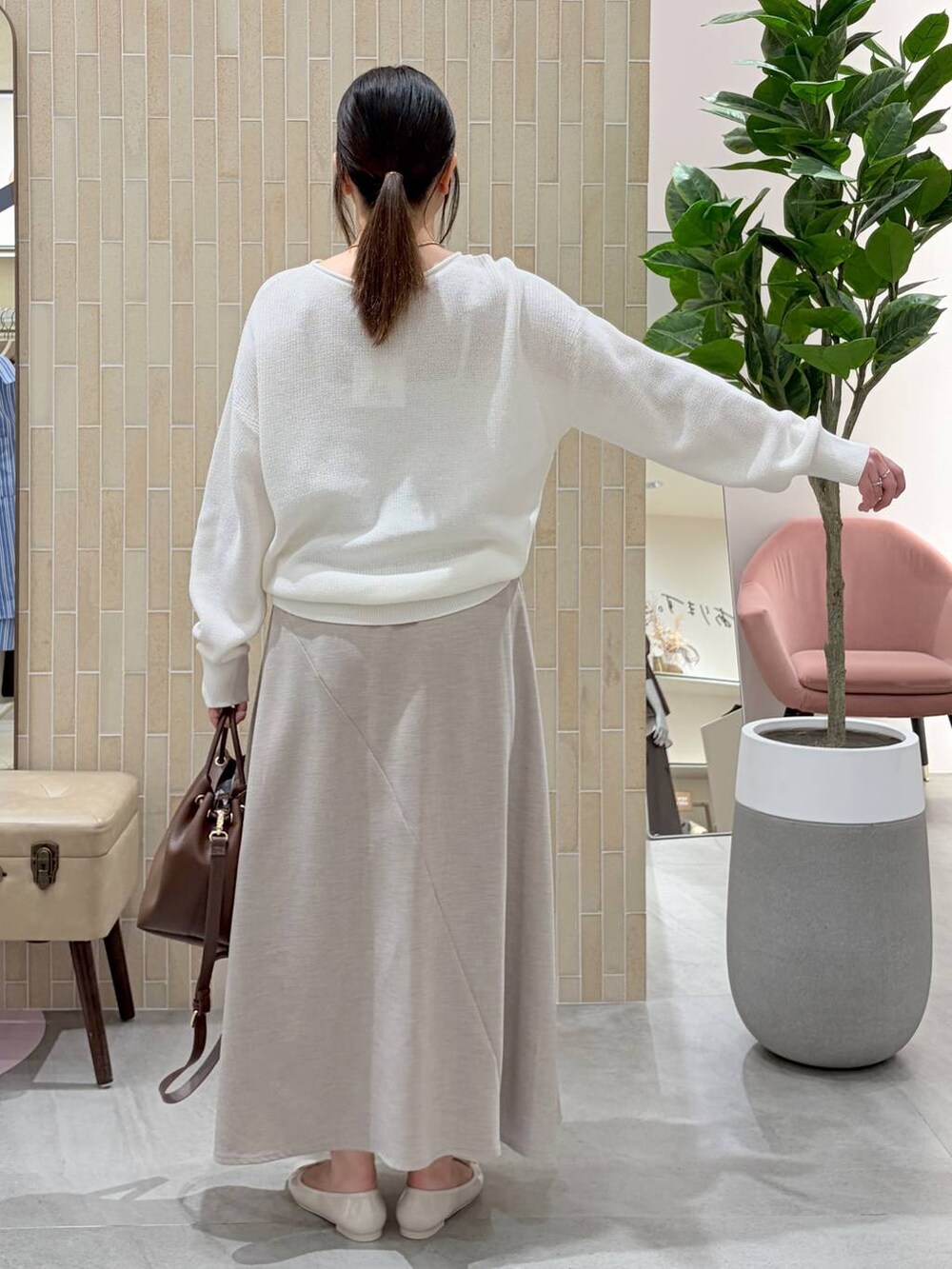 ホワイト系のニット/セーター、ブラウン系のハンドバッグ、ベージュ系のスカートを着用したレディースの春コーディネートの4枚目の写真