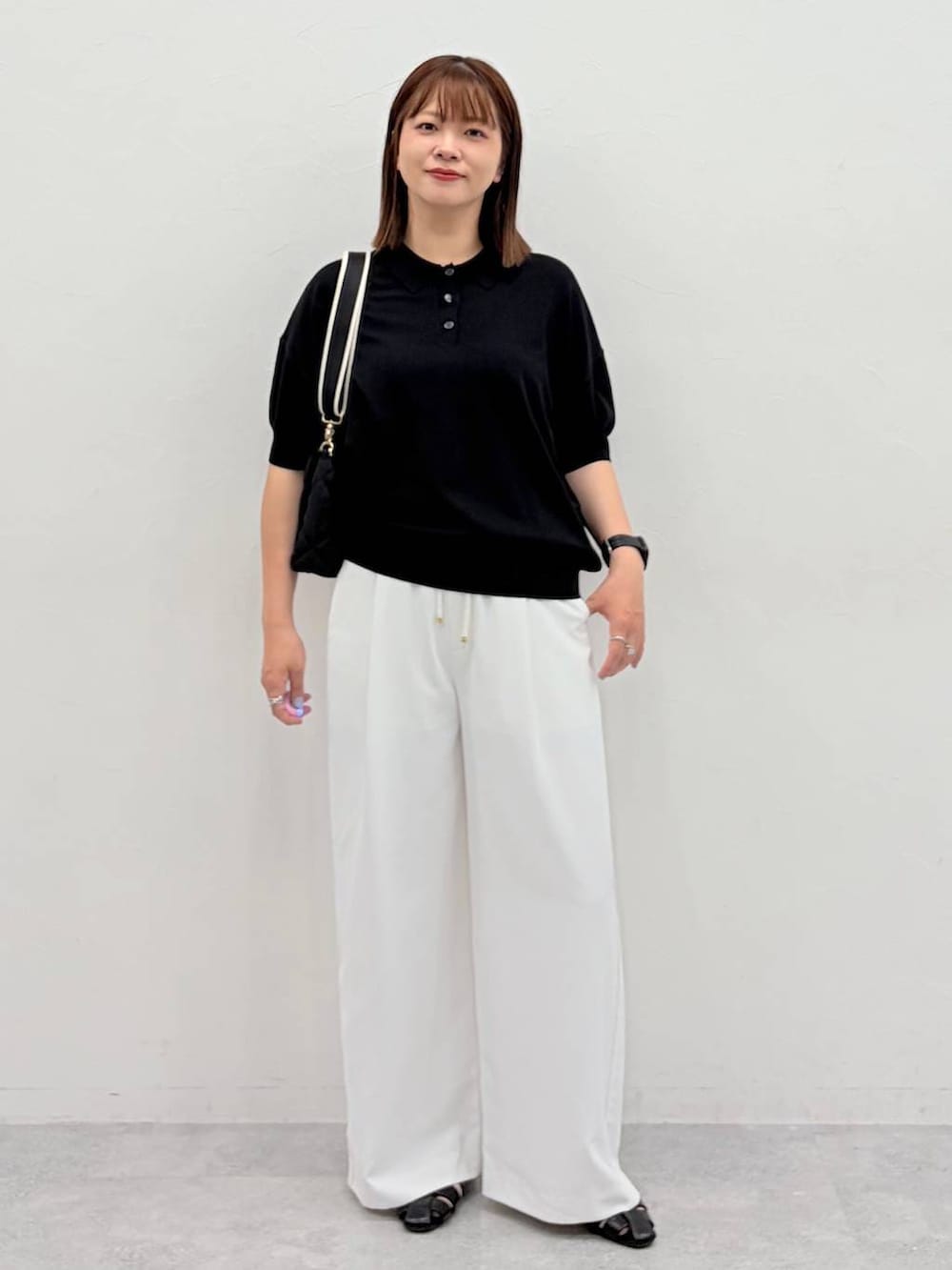 ブラック系のニット/セーター、ブラック系のパンプス、ブラック系のハンドバッグを着用したレディースの夏コーディネートの2枚目の写真
