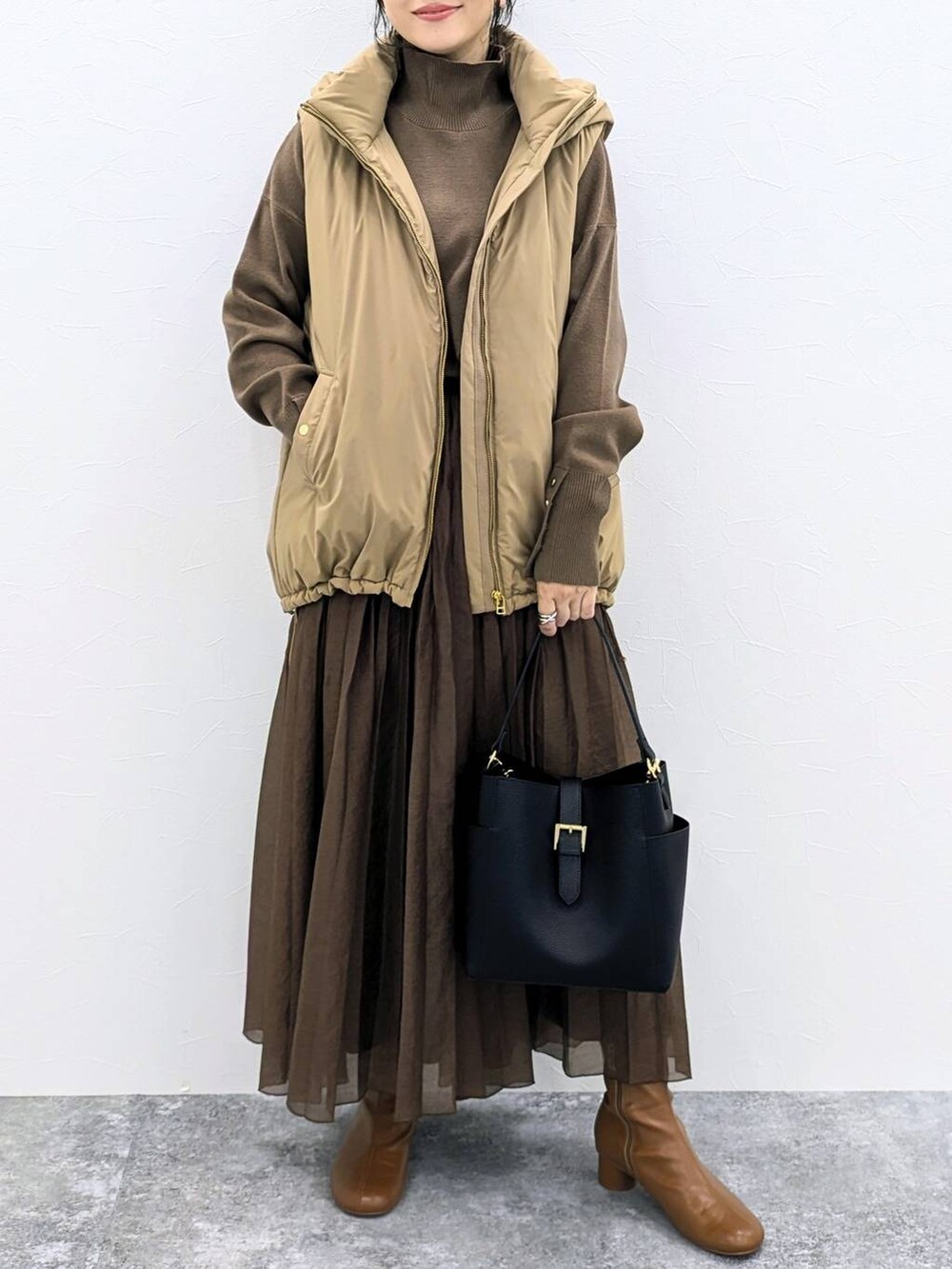 ブラウン系のブーツ、ブラック系のショルダーバッグ、ブラウン系のニット/セーターを着用したレディースの秋コーディネートの6枚目の写真