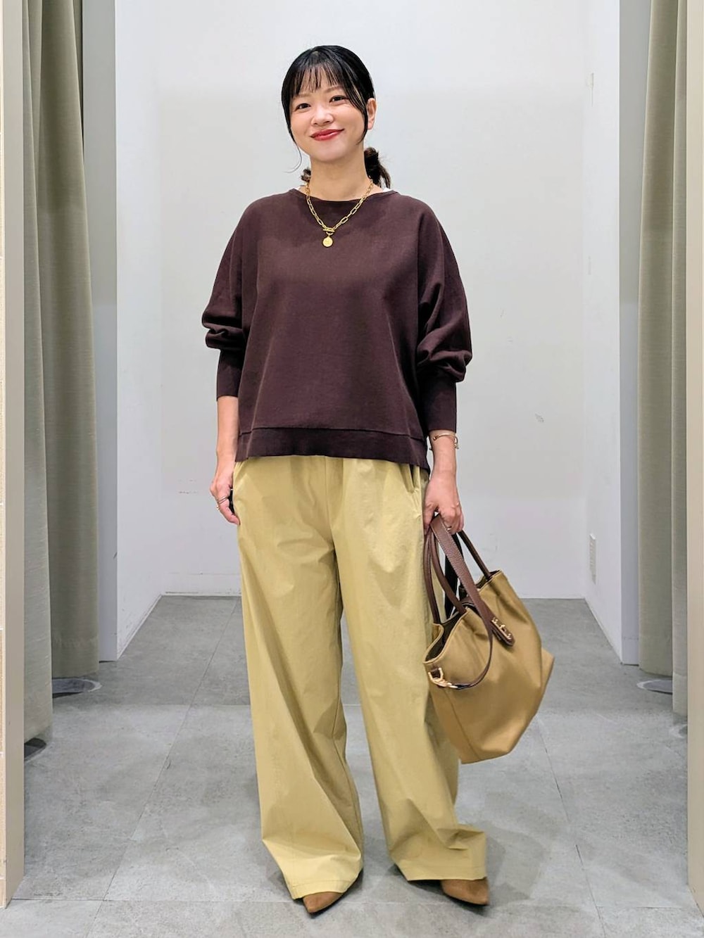 ブラウン系のパンプス、ベージュ系のハンドバッグ、ブラウン系のニット/セーターを着用したレディースの秋コーディネートの2枚目の写真