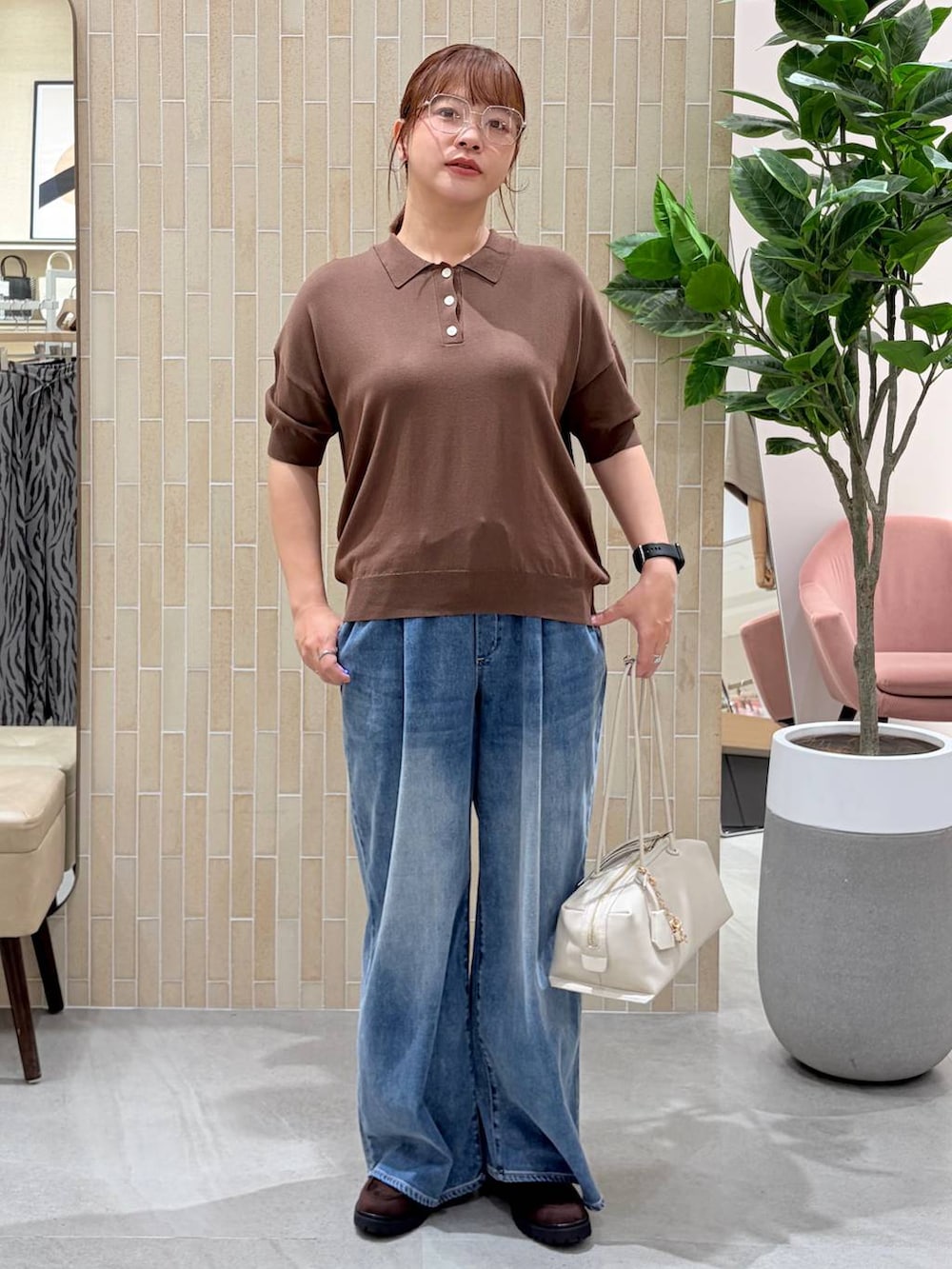 ブラウン系のニット/セーター、ブルー系のデニムパンツ、シルバー系のメガネを着用したレディースの夏コーディネートの2枚目の写真
