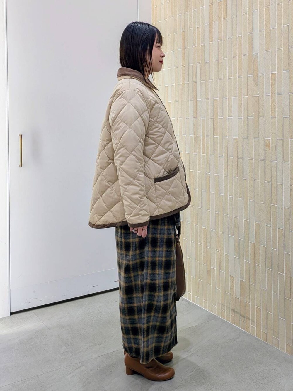 ブラウン系のブーツ、ベージュ系のダウンジャケット/コート、イエロー系のスカートを着用したレディースの冬コーディネートの5枚目の写真