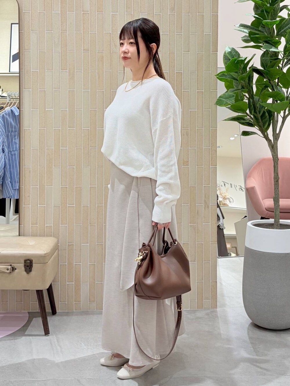 ホワイト系のニット/セーター、ブラウン系のハンドバッグ、ベージュ系のスカートを着用したレディースの春コーディネートの3枚目の写真