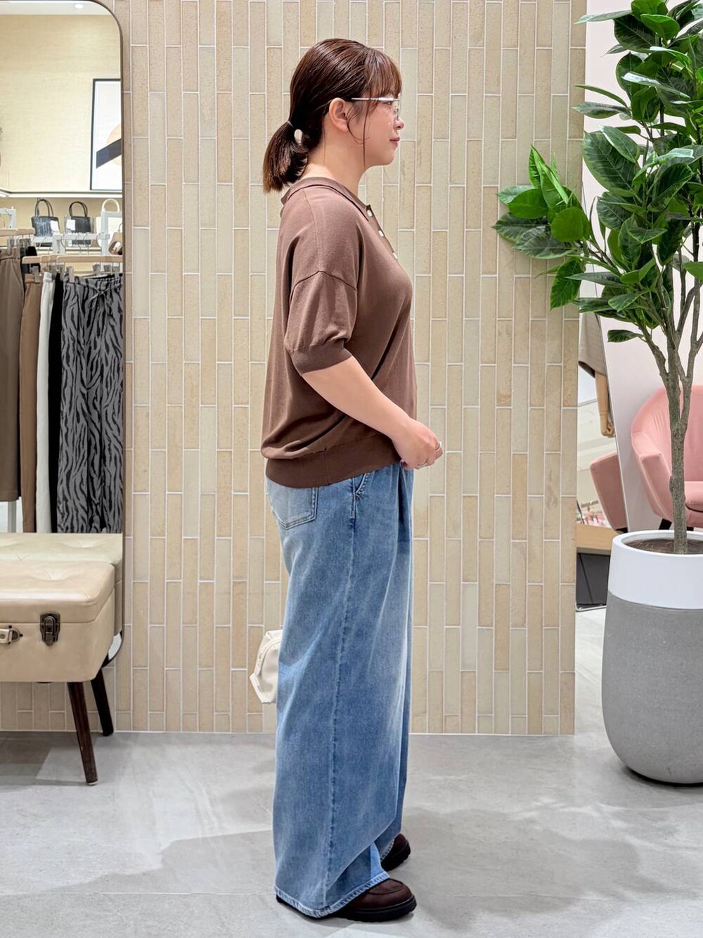 ブラウン系のニット/セーター、ブルー系のデニムパンツ、シルバー系のメガネを着用したレディースの夏コーディネートの5枚目の写真