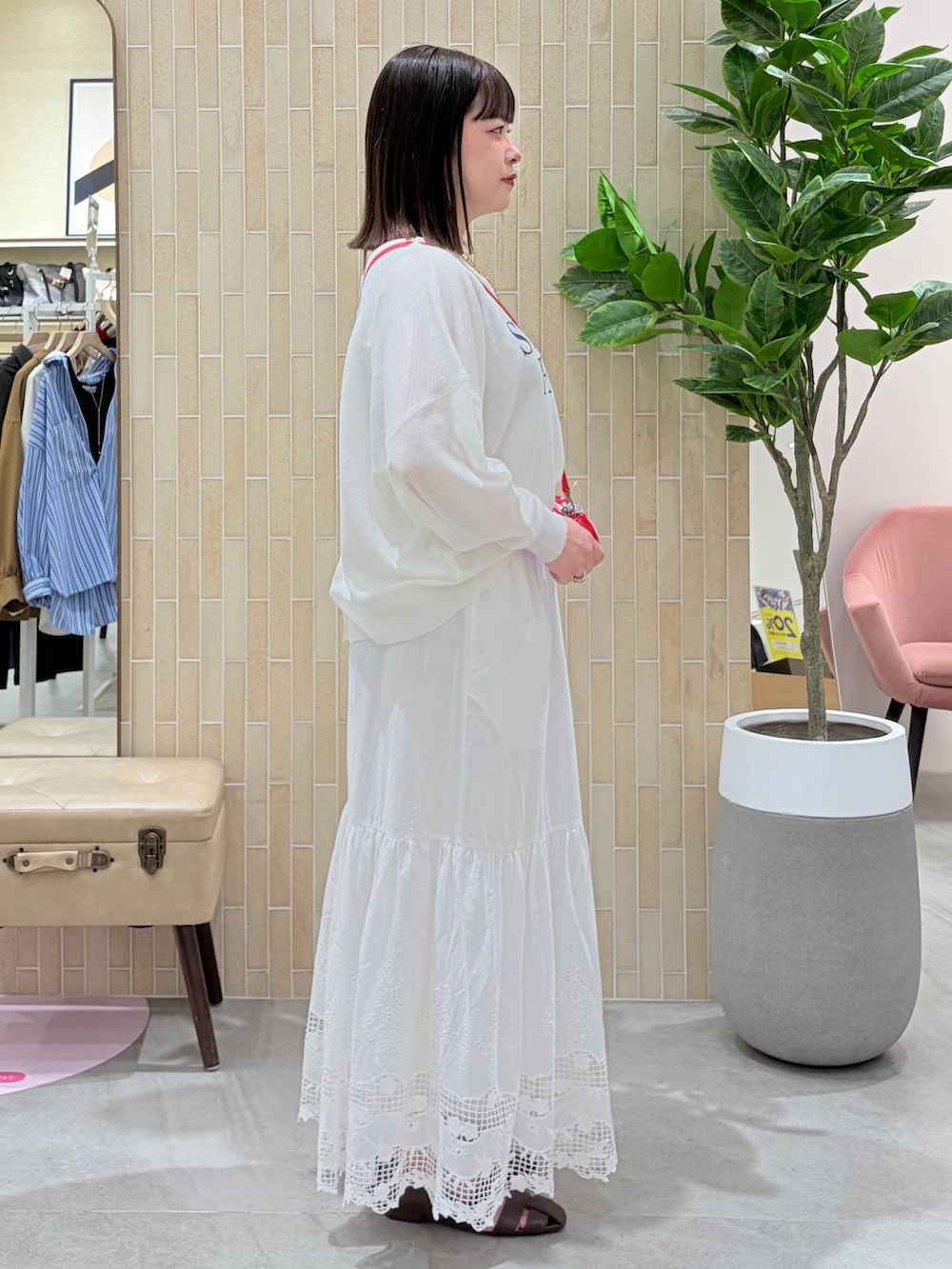 レッド系のハンドバッグ、ブラウン系のパンプス、ホワイト系のスカートを着用したレディースの春コーディネートの5枚目の写真