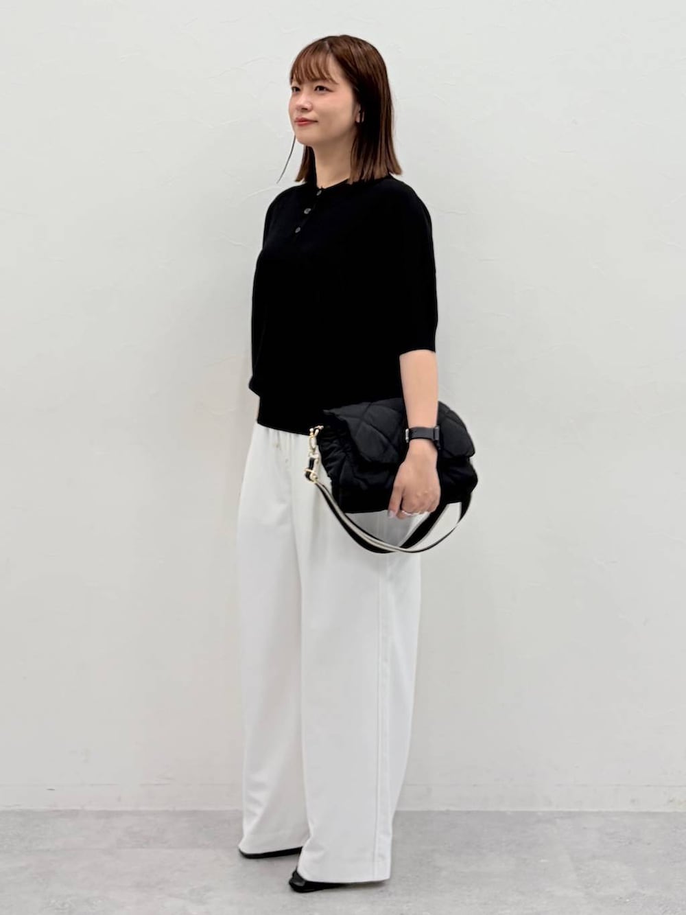 ブラック系のニット/セーター、ブラック系のパンプス、ブラック系のハンドバッグを着用したレディースの夏コーディネートの3枚目の写真