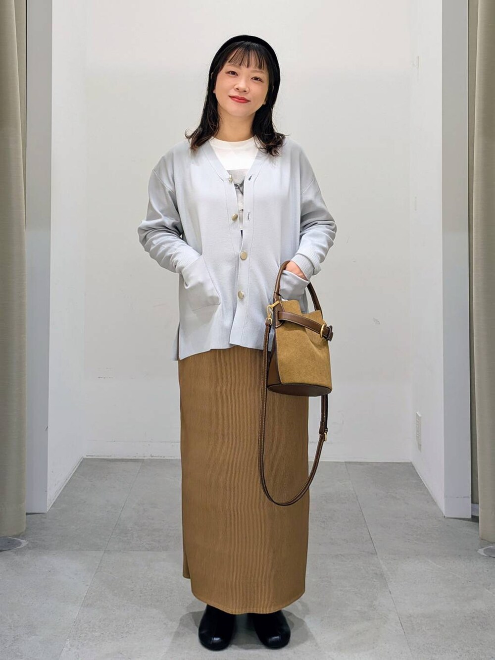 グレー系のカーディガン/ボレロ、ホワイト系のTシャツ/カットソー、ブラック系のブーツを着用したレディースの秋コーディネートの2枚目の写真