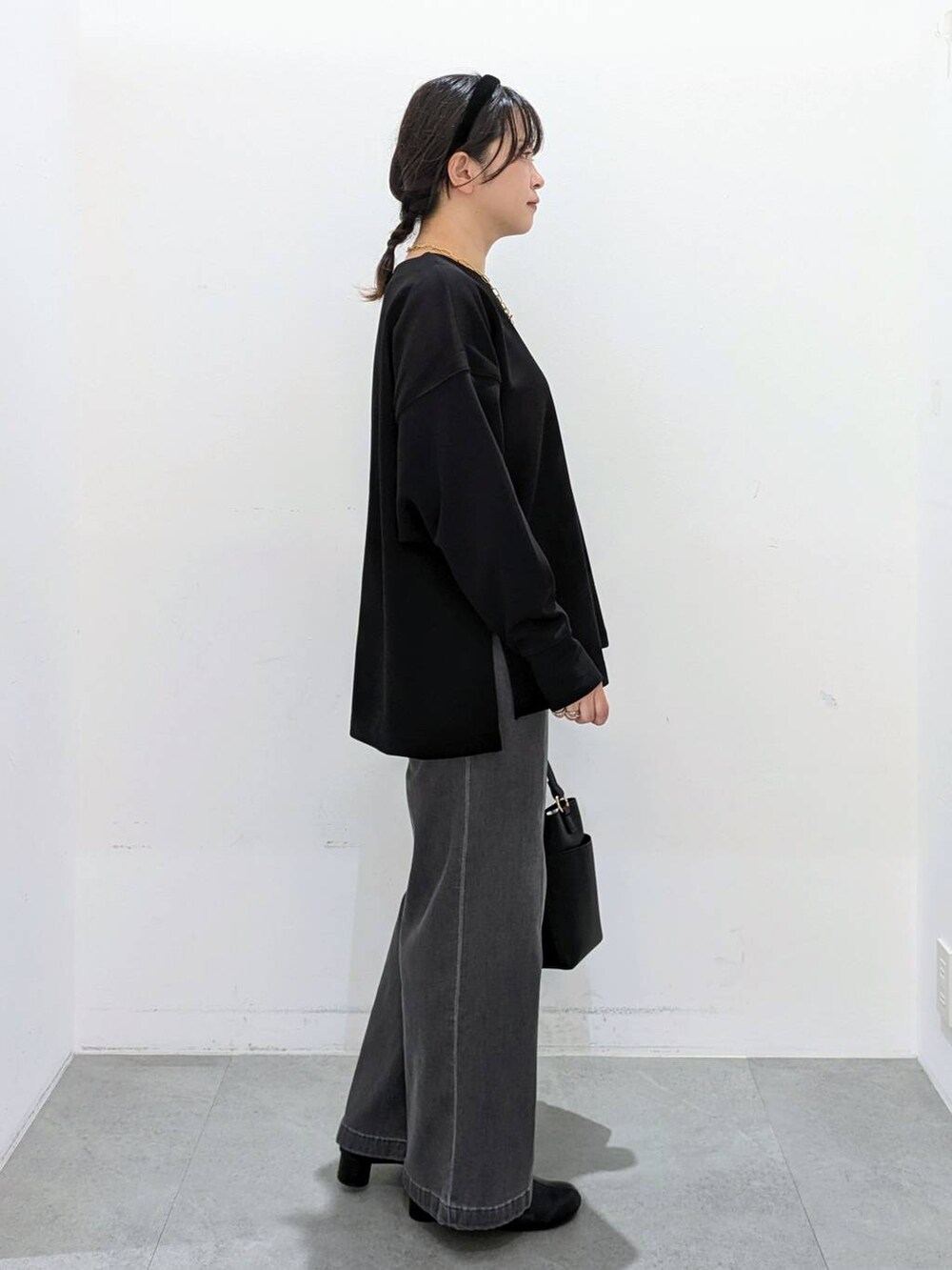 ブラック系のブーツ、ブラック系のショルダーバッグ、ブラック系のデニムパンツを着用したレディースの秋コーディネートの5枚目の写真