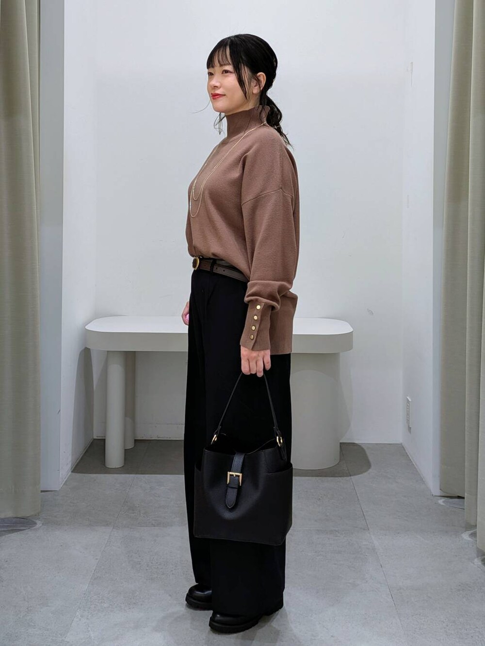 ブラック系のブーツ、ブラック系のショルダーバッグ、ブラウン系のニット/セーターを着用したレディースの秋コーディネートの3枚目の写真