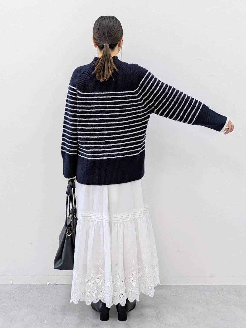ブラック系のブーツ、ブルー系のニット/セーター、ホワイト系のスカートを着用したレディースの冬コーディネートの4枚目の写真