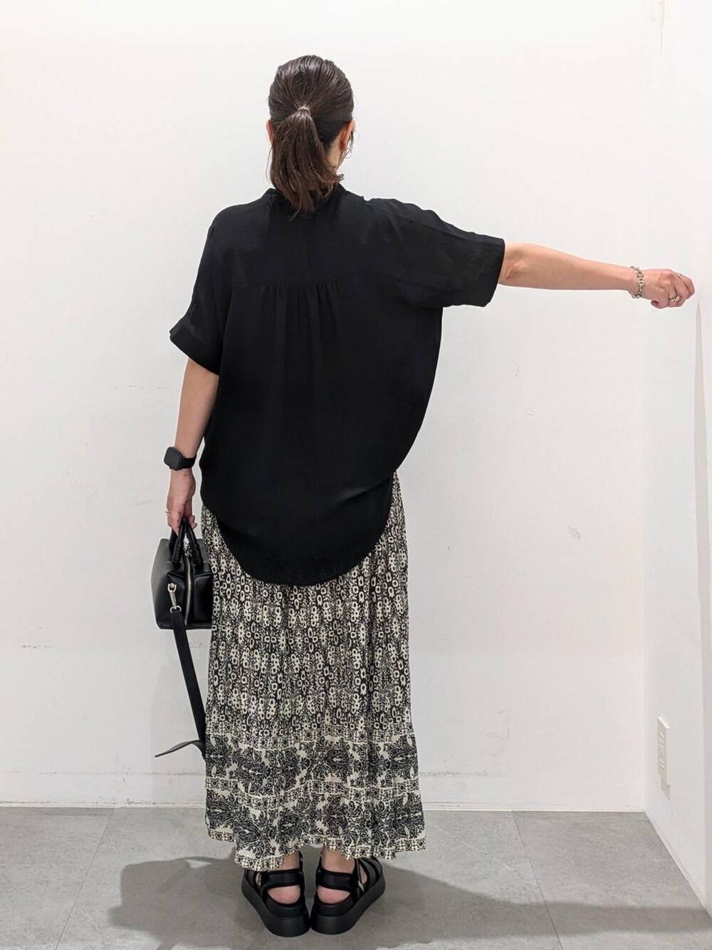 ブラック系のスカート、ブラック系のサンダル、ブラック系のTシャツ/カットソーを着用したレディースの夏コーディネートの5枚目の写真