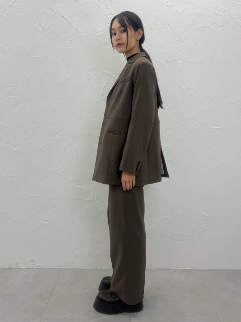 ブラウン系のブーツ、ブラウン系のテーラードジャケット、ブラウン系のスラックスを着用したレディースの夏コーディネートの5枚目の写真