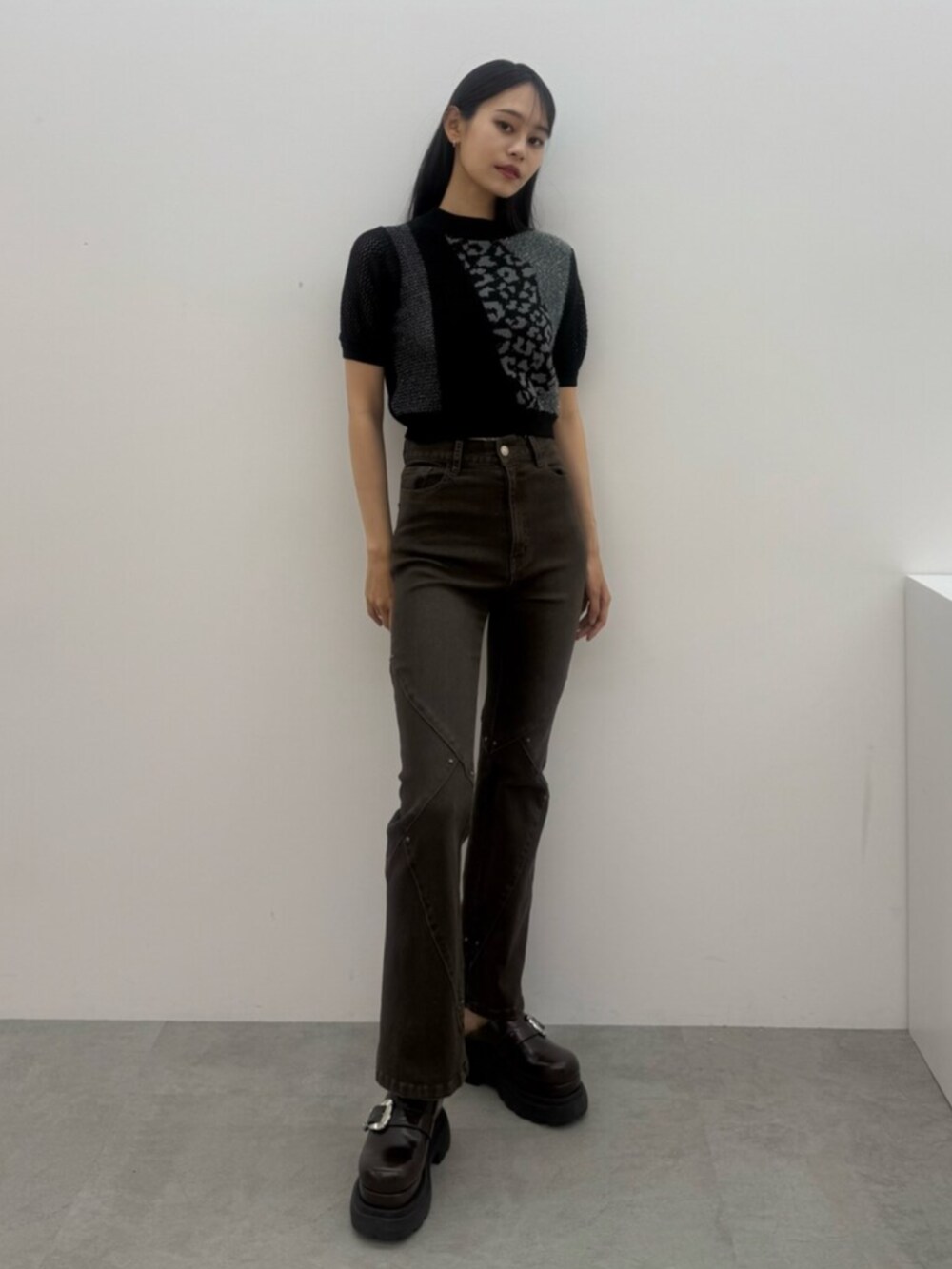 ブラウン系のデニムパンツ、ブラック系のニット/セーター、ブラウン系のサンダルを着用したレディースの夏コーディネートの2枚目の写真