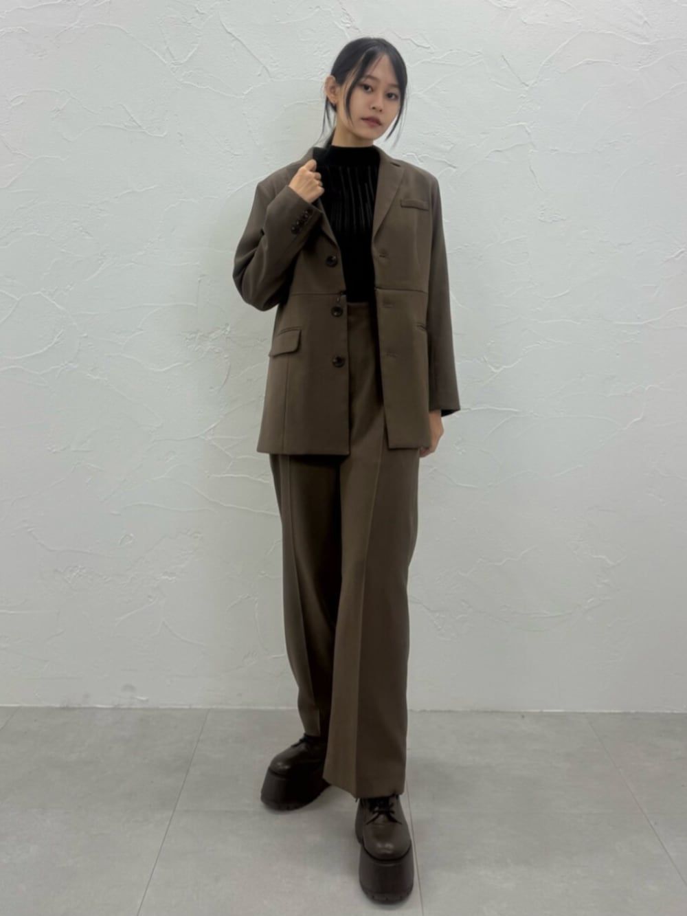 ブラウン系のブーツ、ブラウン系のテーラードジャケット、ブラウン系のスラックスを着用したレディースの夏コーディネートの4枚目の写真