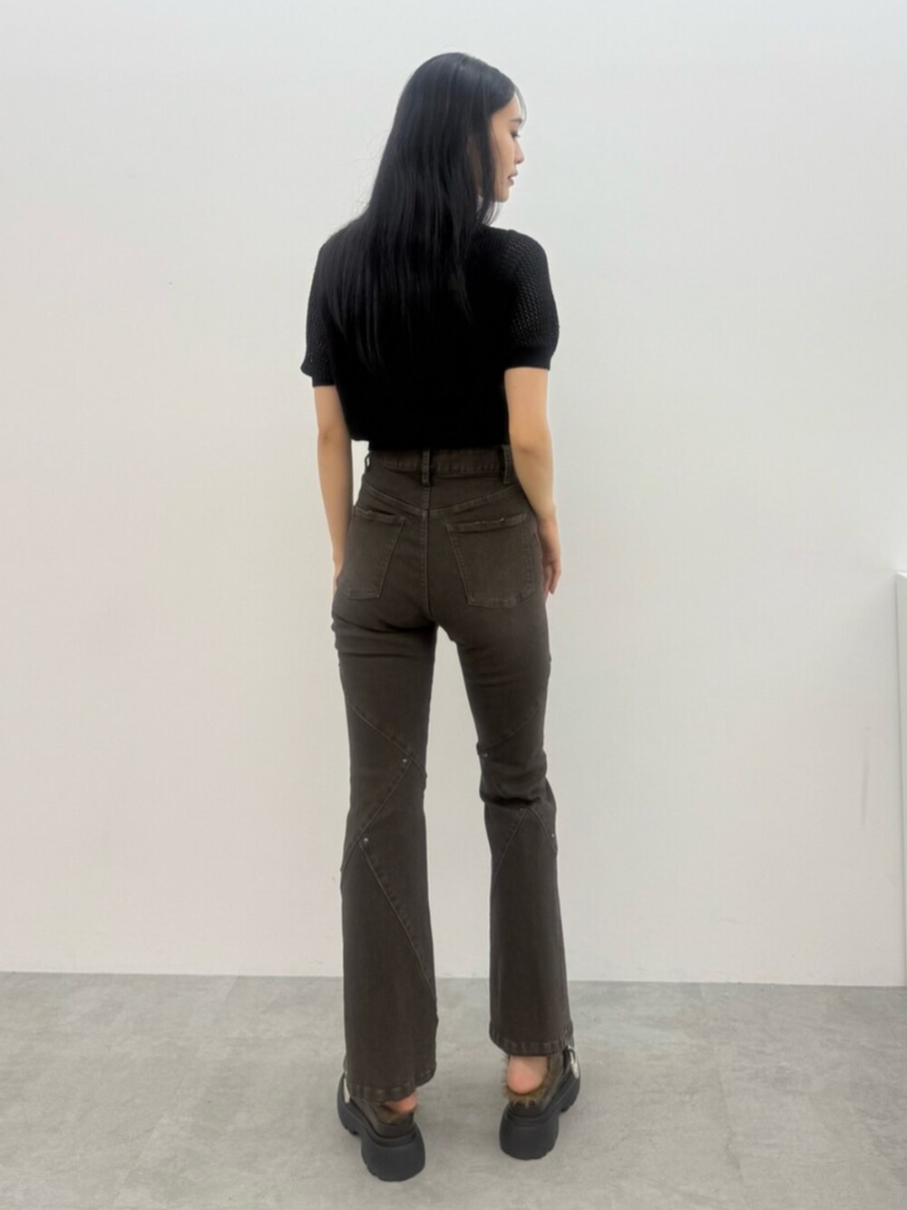 ブラウン系のデニムパンツ、ブラック系のニット/セーター、ブラウン系のサンダルを着用したレディースの夏コーディネートの3枚目の写真