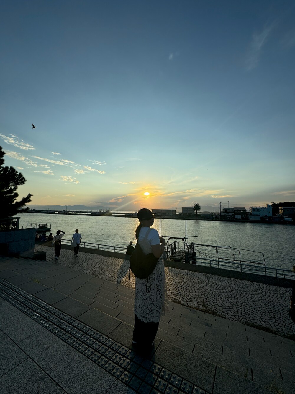 ベージュ系のワンピース、グレー系のデニムパンツ、ホワイト系のスニーカーを着用したレディースの秋コーディネートの3枚目の写真