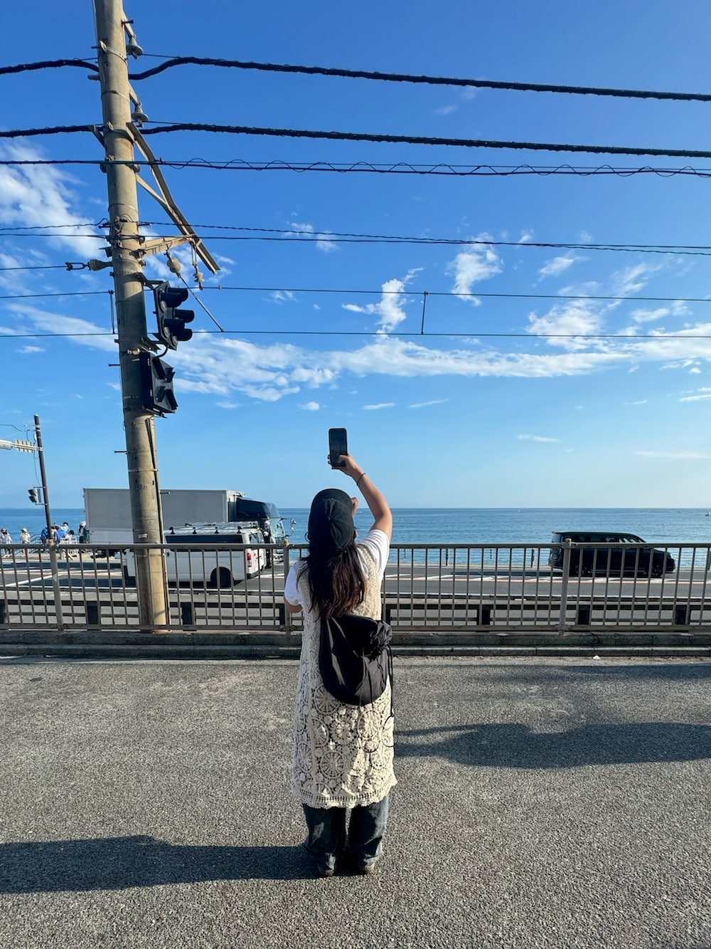 ベージュ系のワンピース、グレー系のデニムパンツ、ホワイト系のスニーカーを着用したレディースの秋コーディネートの2枚目の写真