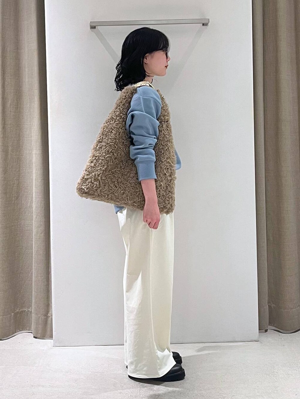 ブラウン系のハンドバッグ、ブラック系のブーツ、ブルー系のスウェットを着用したレディースの秋コーディネートの4枚目の写真