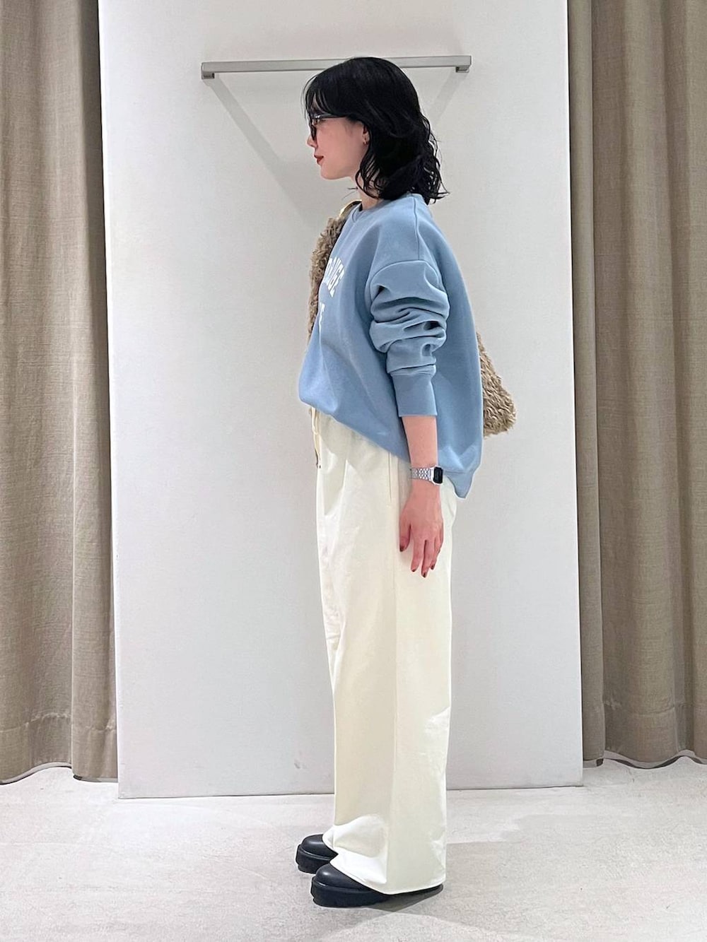 ブラウン系のハンドバッグ、ブラック系のブーツ、ブルー系のスウェットを着用したレディースの秋コーディネートの2枚目の写真