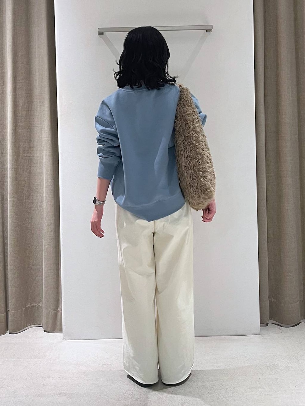 ブラウン系のハンドバッグ、ブラック系のブーツ、ブルー系のスウェットを着用したレディースの秋コーディネートの3枚目の写真