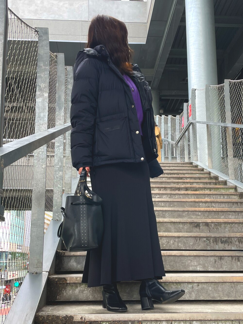 ブラック系のショルダーバッグ、ブラック系のダウンジャケット/コート、パープル系のカーディガン/ボレロを着用したレディースの冬コーディネートの2枚目の写真