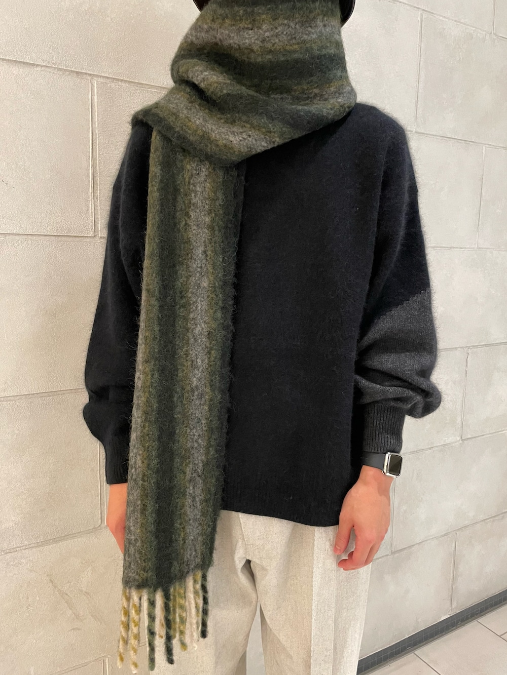 ホワイト系のデニムパンツ、ブラック系のニット/セーター、グリーン系のマフラーを着用したメンズの冬コーディネートの2枚目の写真