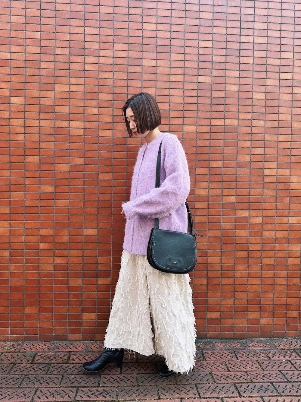 ピンク系のカーディガン/ボレロ、ホワイト系のワンピース、ブラック系のブーツを着用したレディースの冬コーディネートの2枚目の写真