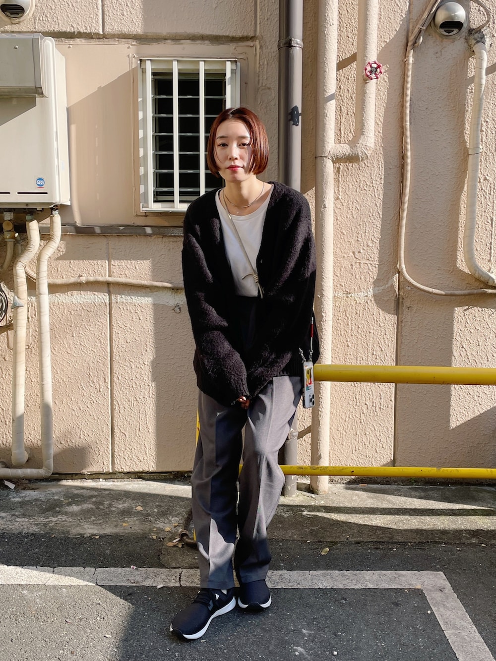 ブラック系のカーディガン/ボレロ、ホワイト系のTシャツ/カットソー、グレー系のスラックスを着用したレディースの秋コーディネートの3枚目の写真