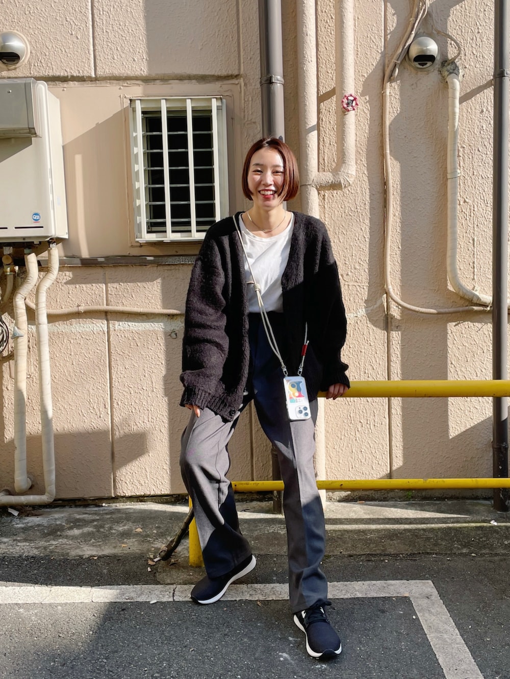 ブラック系のカーディガン/ボレロ、ホワイト系のTシャツ/カットソー、グレー系のスラックスを着用したレディースの秋コーディネートの2枚目の写真