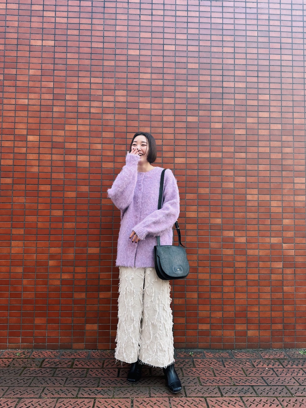 ピンク系のカーディガン/ボレロ、ホワイト系のワンピース、ブラック系のブーツを着用したレディースの冬コーディネートの3枚目の写真