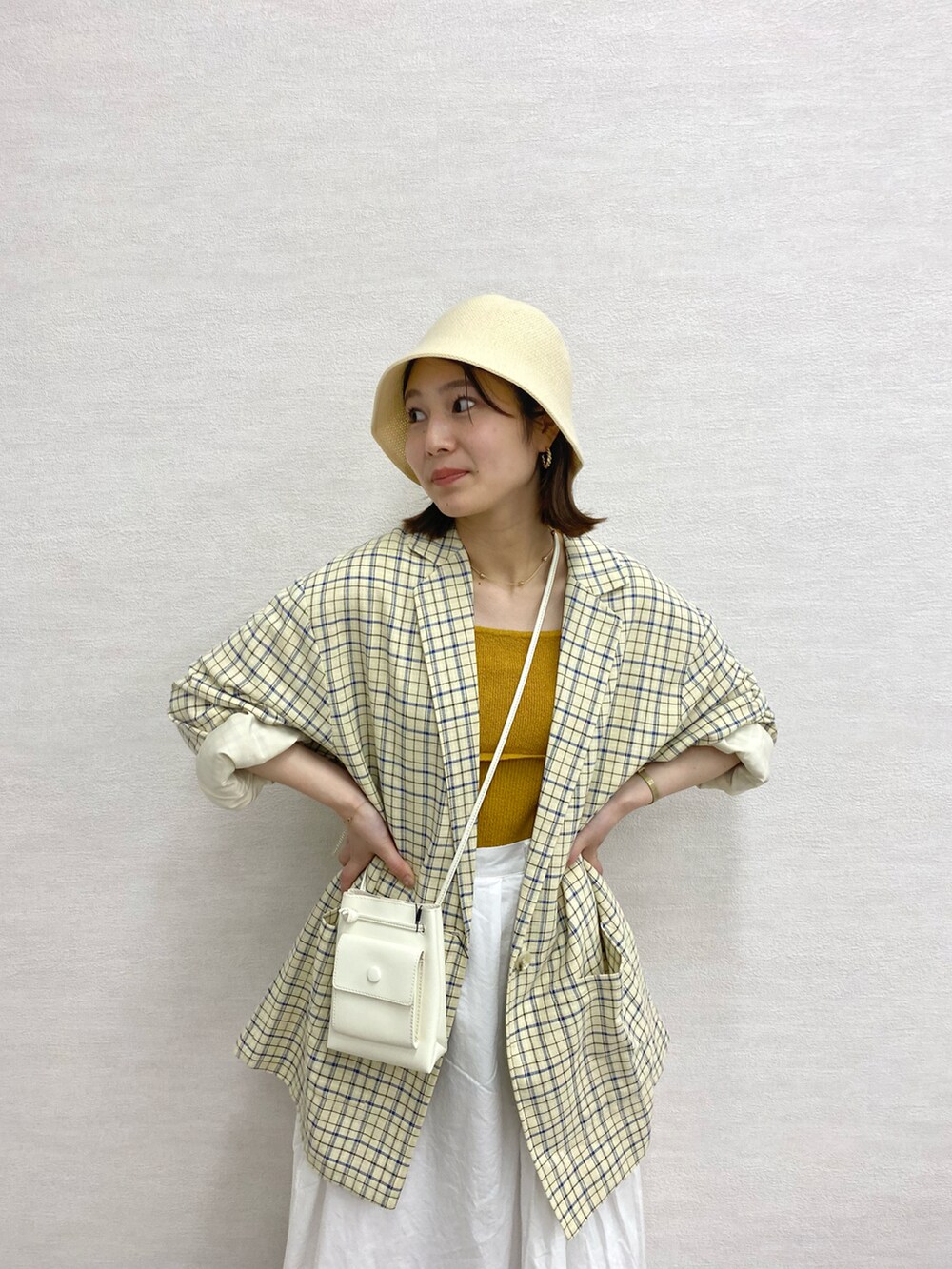 ホワイト系のスカート、イエロー系のキャミソール、ピンク系のショルダーバッグを着用したレディースの春コーディネートの2枚目の写真