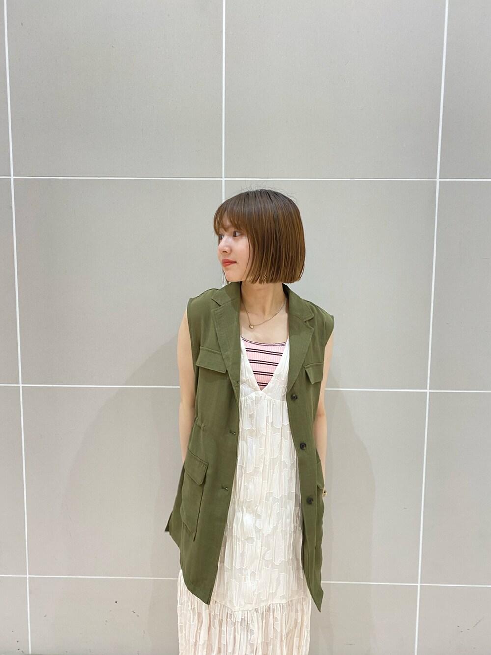 ホワイト系のワンピース、グリーン系のベスト、ホワイト系のサンダルを着用したレディースの夏コーディネートの2枚目の写真