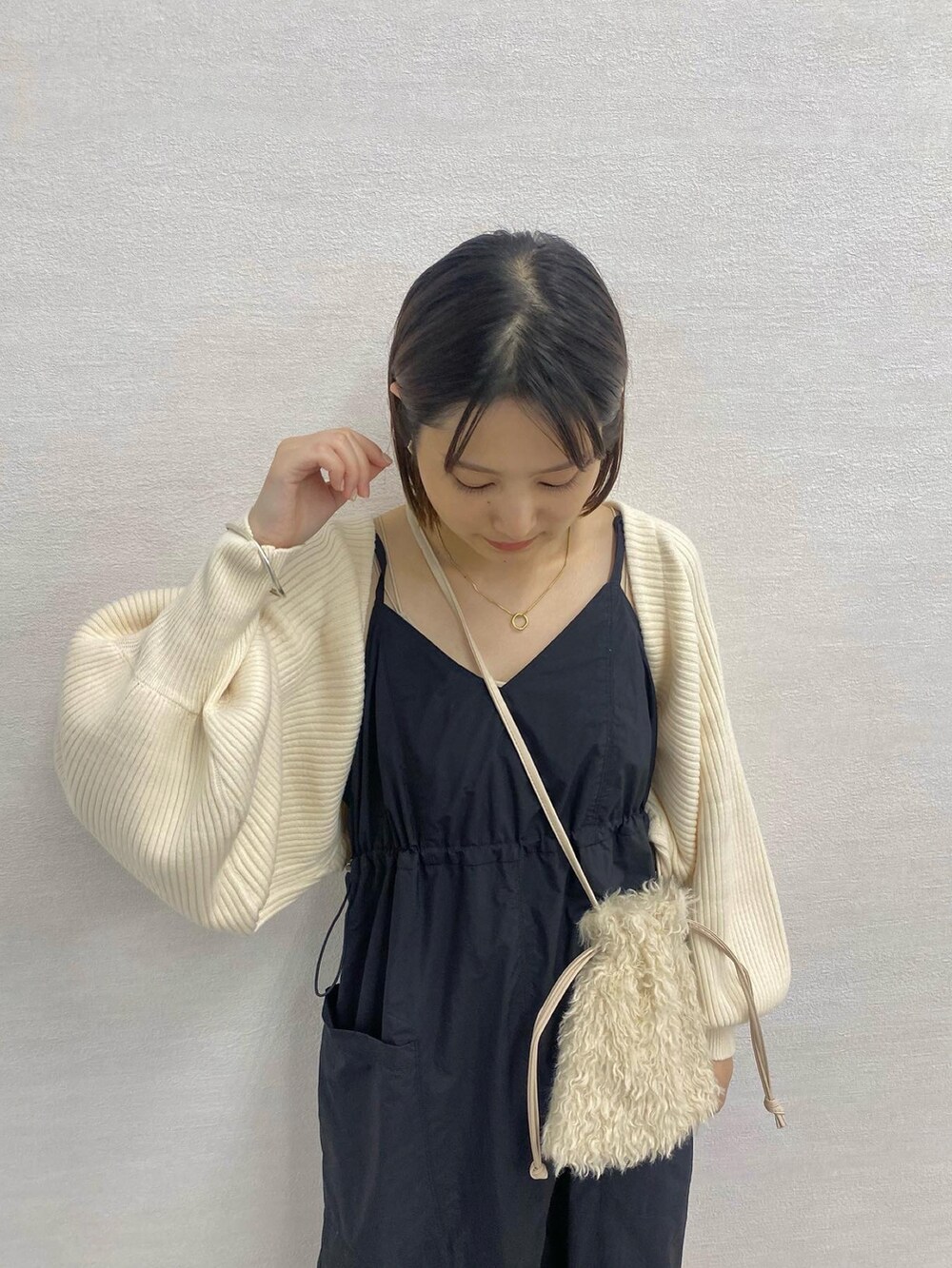 ブラック系のブーツ、ホワイト系のワンピース、ホワイト系のショルダーバッグを着用したレディースの秋コーディネートの2枚目の写真