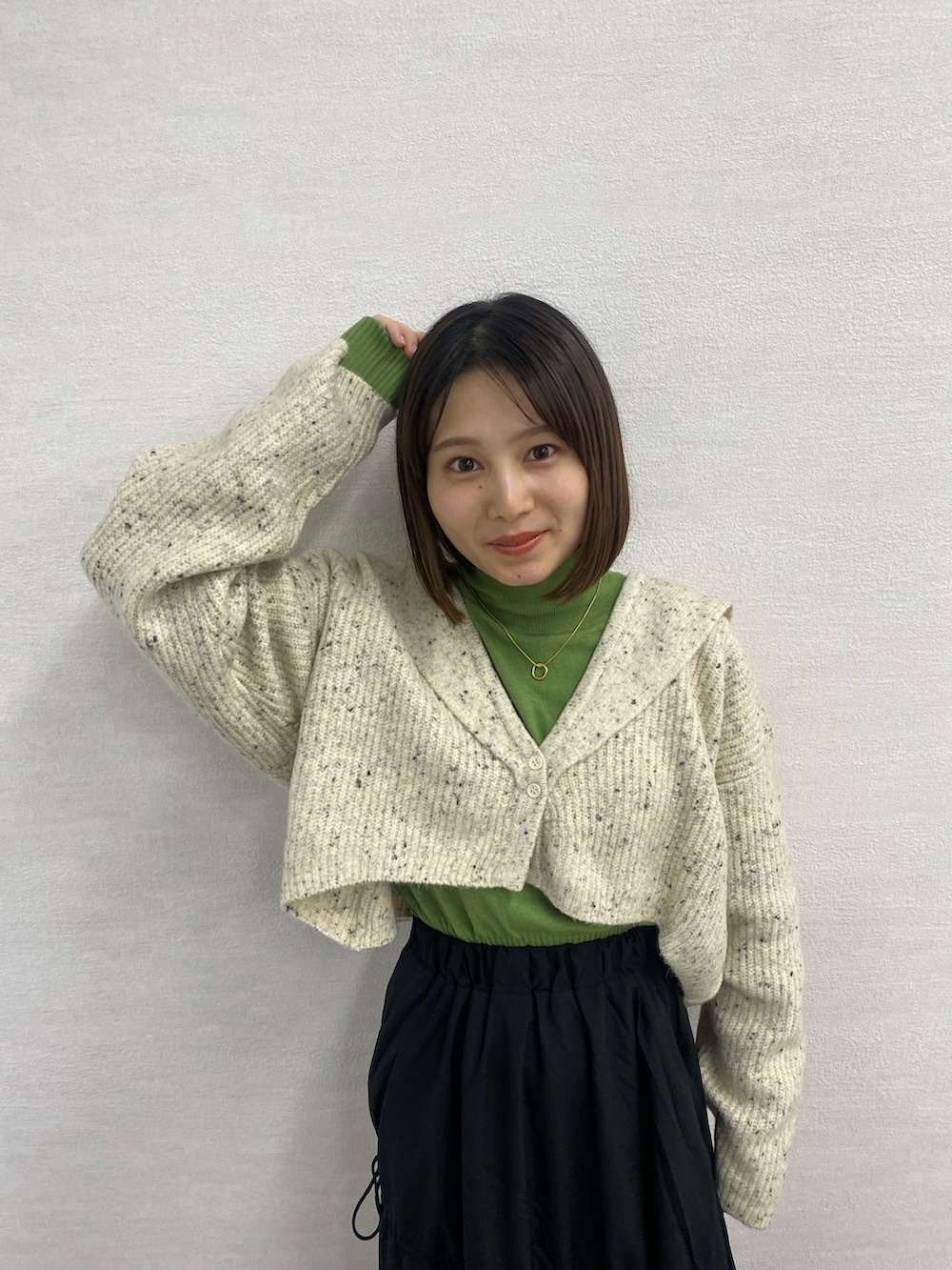 ブラック系のブーツ、ホワイト系のカーディガン/ボレロ、ブラック系のスカートを着用したレディースの秋コーディネートの2枚目の写真