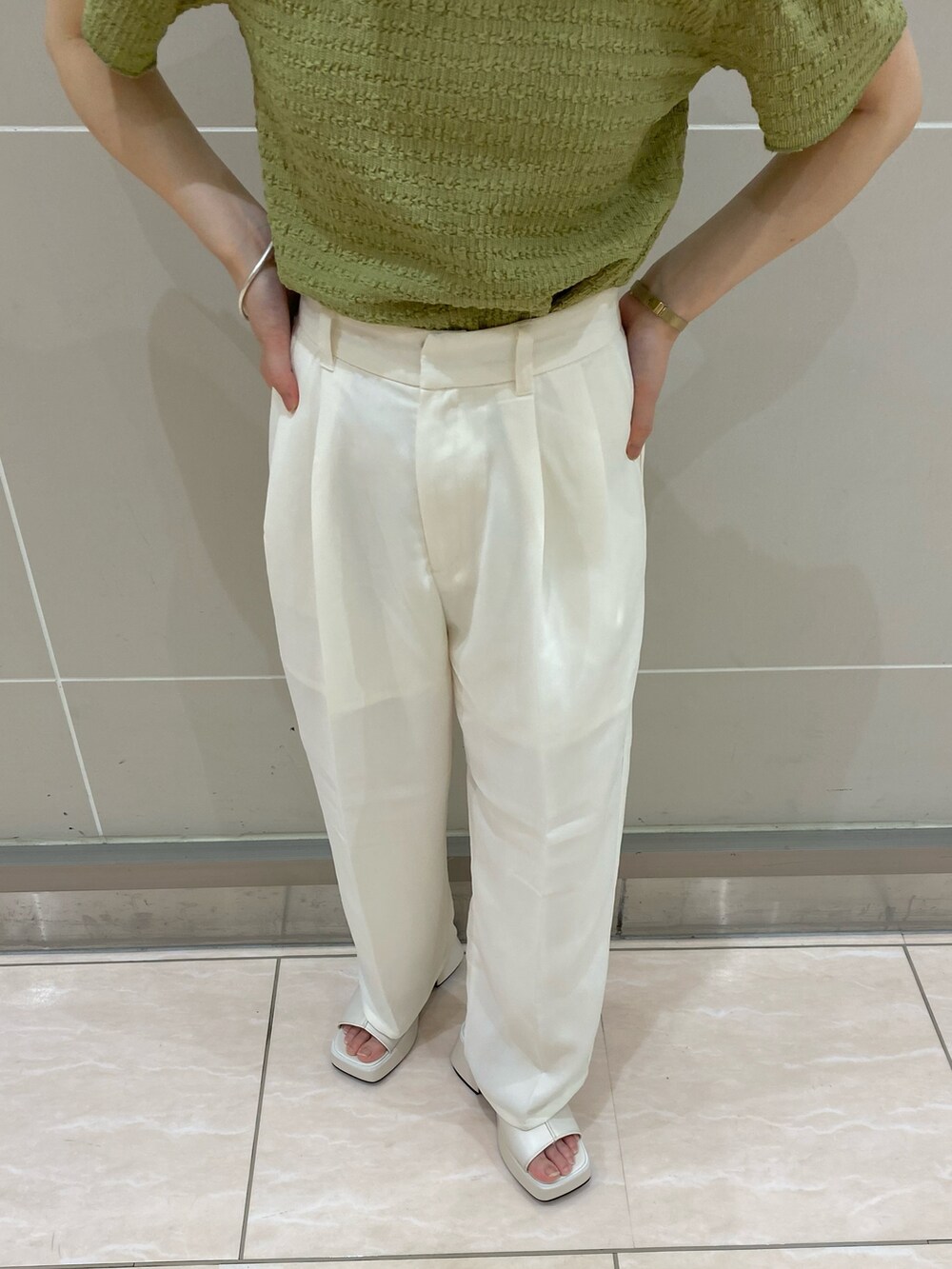 ブラウン系のボストンバッグ、ホワイト系のスラックス、ブラック系のサンダルを着用したレディースの夏コーディネートの3枚目の写真