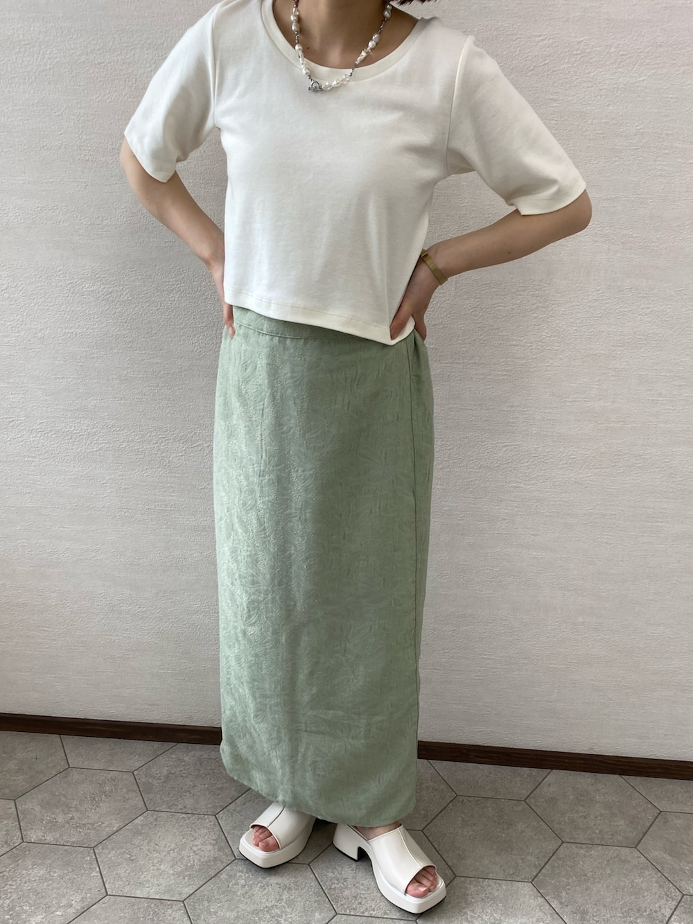 グリーン系のスカート、ホワイト系のサンダル、ホワイト系のTシャツ/カットソーを着用したレディースの夏コーディネートの2枚目の写真