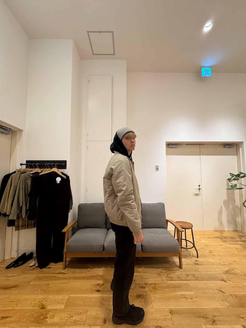 ベージュ系のジャケット/アウター、ブラック系のパーカー、ブラック系のデニムパンツを着用したメンズの秋コーディネートの3枚目の写真