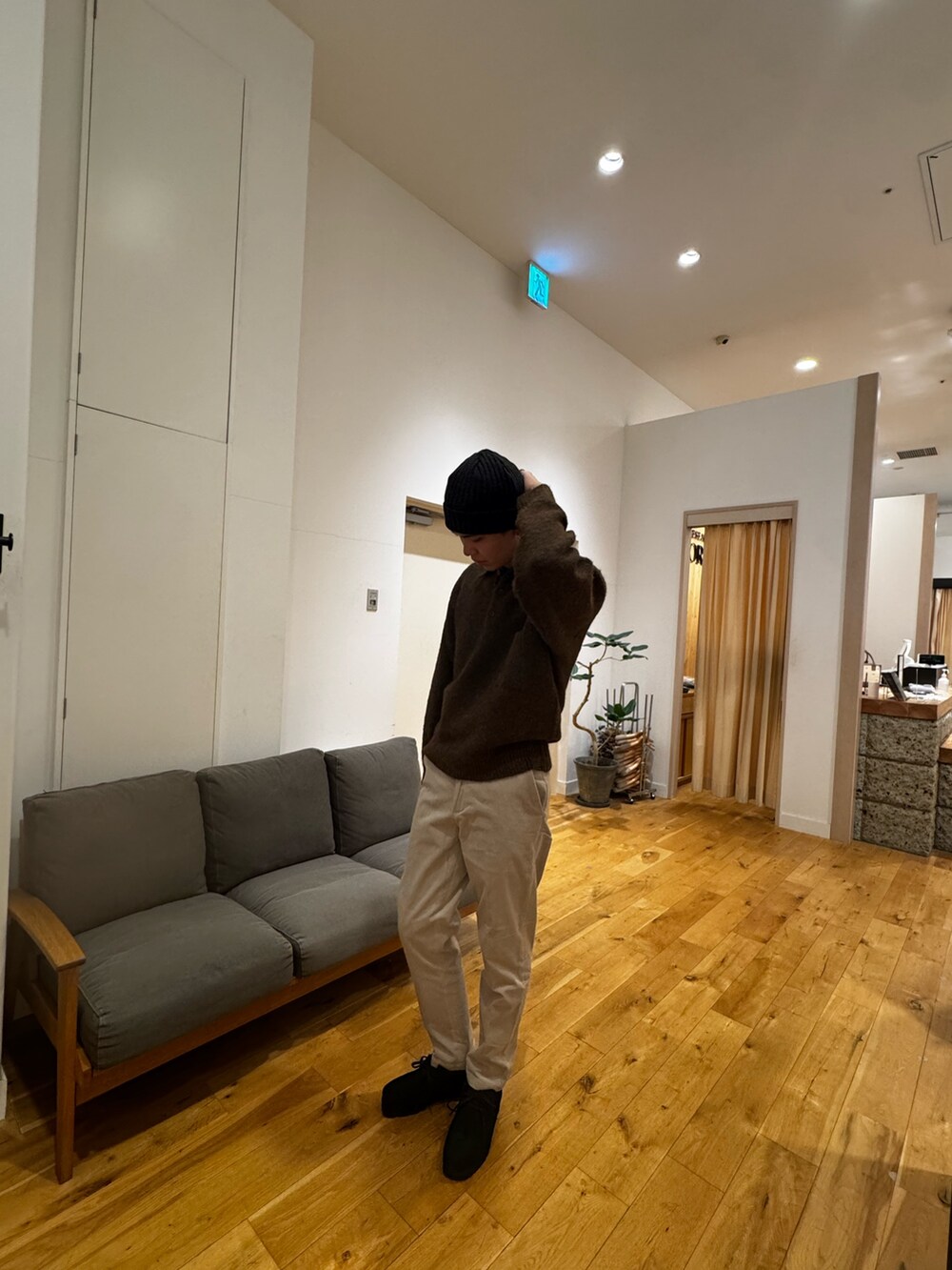 ブラウン系のニット/セーター、ホワイト系のその他パンツ、ブラック系のブーツを着用したメンズの秋コーディネートの5枚目の写真