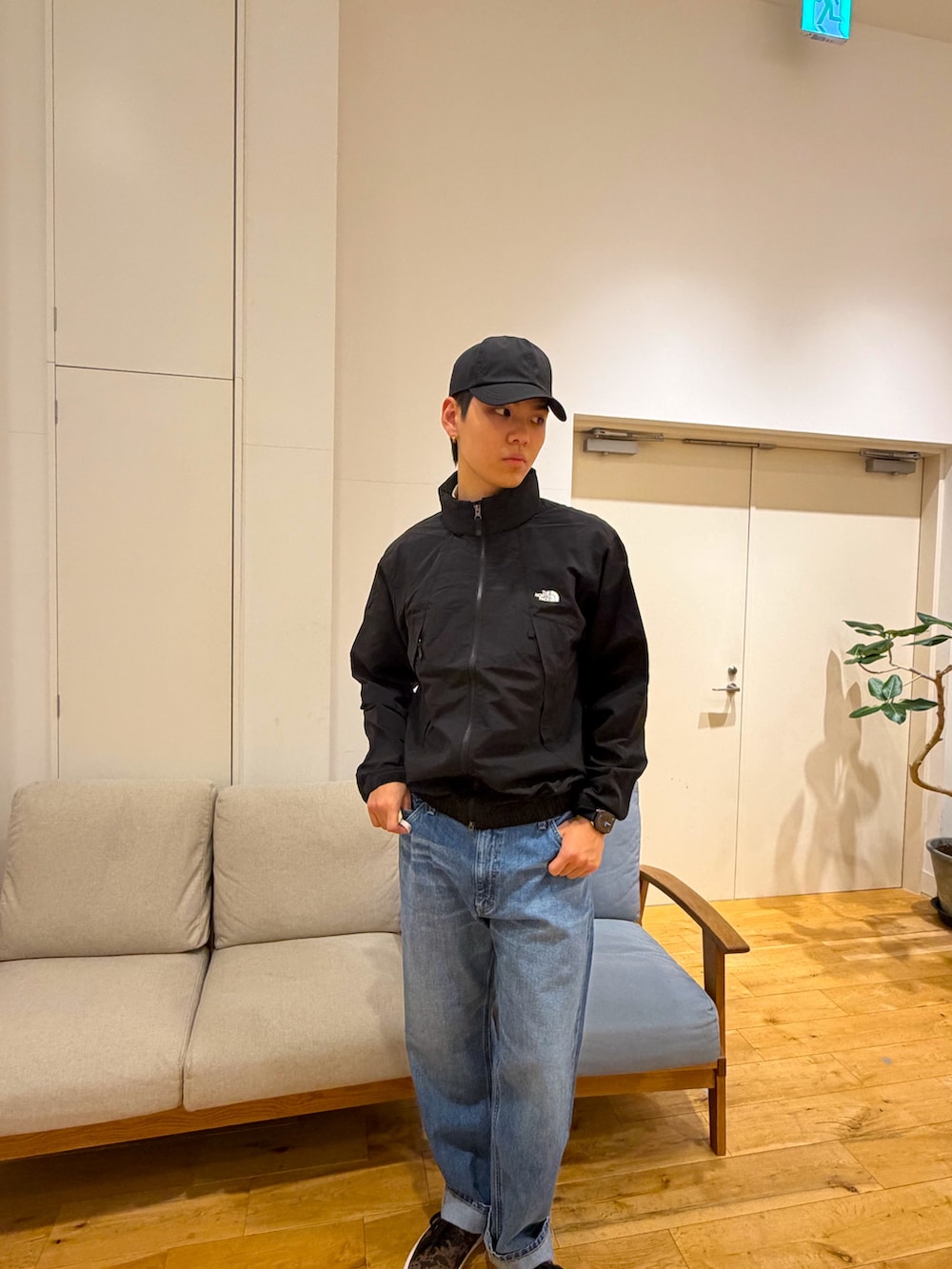 ブラック系のブルゾン、ブルー系のデニムパンツ、ブラウン系のスニーカーを着用したメンズの冬コーディネートの3枚目の写真